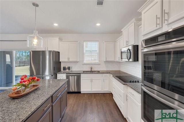 kitchen featuring visible vents, backsplash, stainless steel appliances, white cabinetry, and a sink