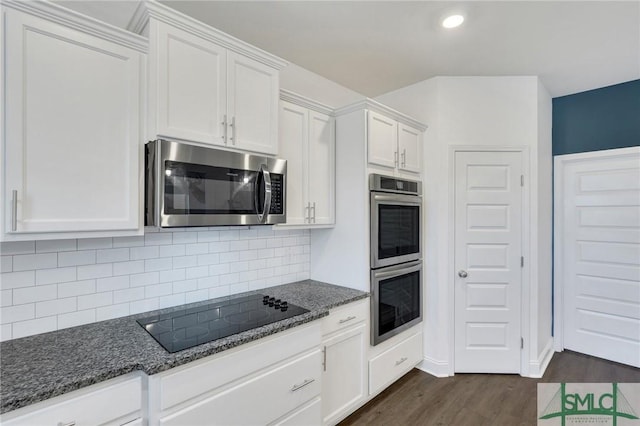 kitchen with dark stone counters, stainless steel appliances, dark wood-type flooring, white cabinetry, and tasteful backsplash