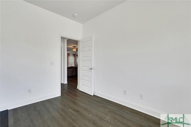 empty room featuring baseboards and dark wood-style flooring