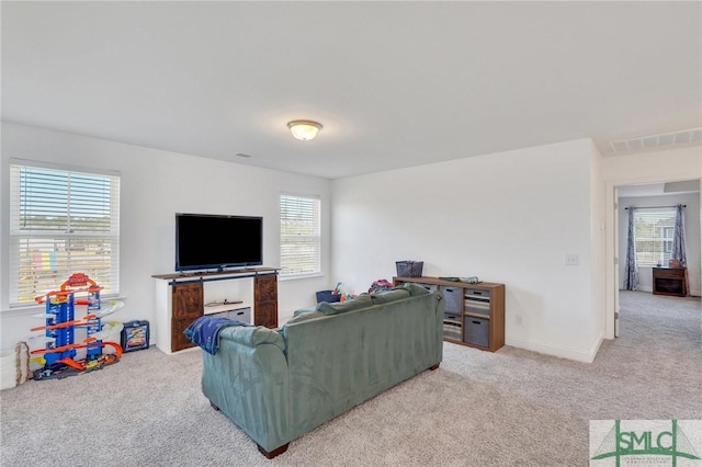 carpeted living room with visible vents, plenty of natural light, and baseboards