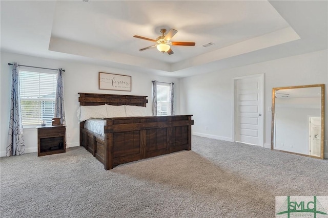 bedroom featuring a raised ceiling, baseboards, and carpet floors