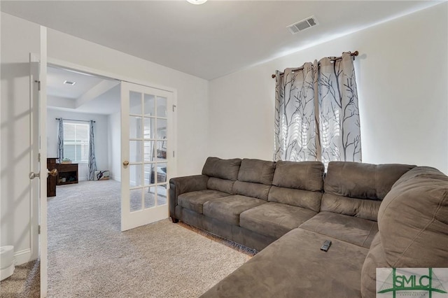 carpeted living area featuring visible vents and french doors