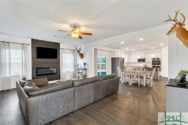 living area with dark wood finished floors, recessed lighting, a fireplace, and ceiling fan