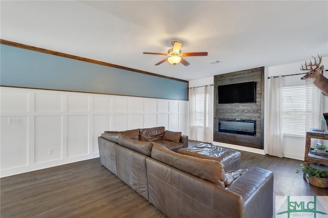 living room with ceiling fan, dark wood-style floors, a fireplace, and a decorative wall