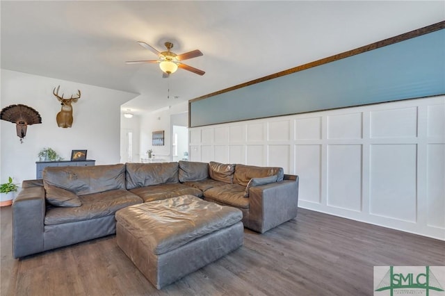 living room with a decorative wall, wood finished floors, and ceiling fan