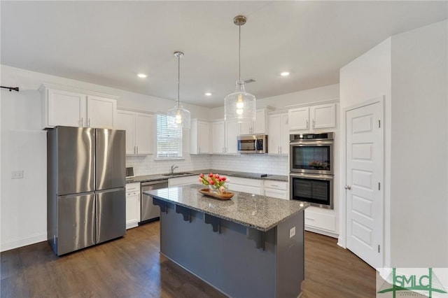 kitchen featuring dark wood-style flooring, a sink, white cabinets, appliances with stainless steel finishes, and a center island