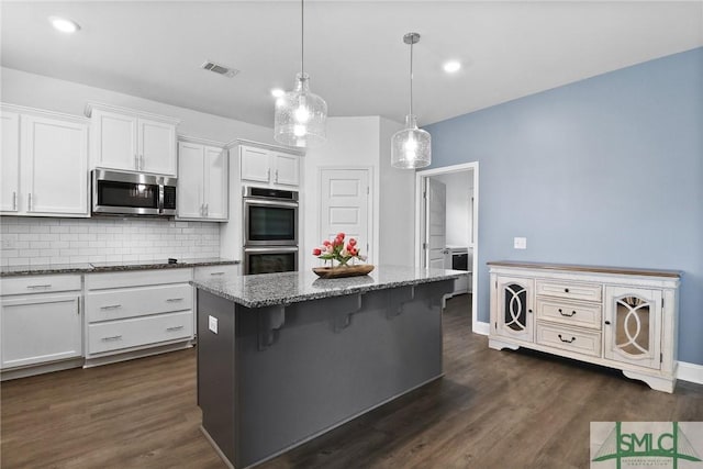 kitchen featuring white cabinets, appliances with stainless steel finishes, stone counters, tasteful backsplash, and visible vents