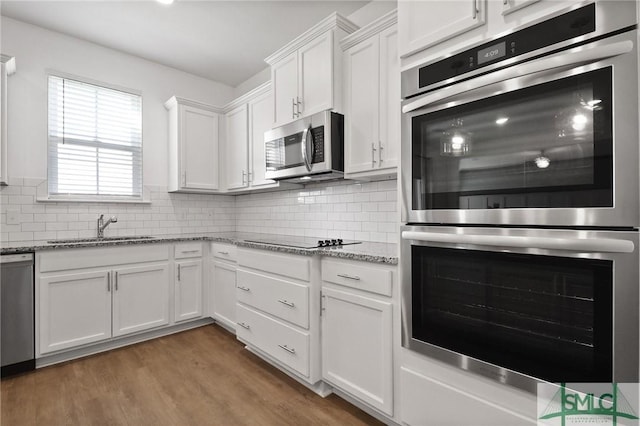 kitchen with light stone counters, a sink, white cabinetry, and stainless steel appliances