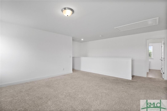 unfurnished room featuring baseboards, carpet, and attic access