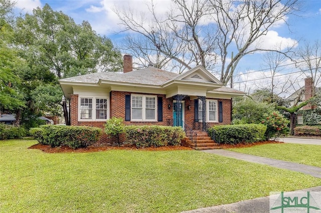 view of front of house featuring brick siding, a chimney, and a front lawn