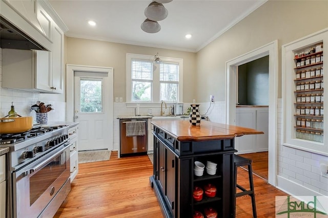 kitchen featuring light wood-type flooring, custom range hood, ornamental molding, white cabinets, and stainless steel appliances