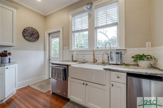 kitchen featuring wood finished floors, ornamental molding, a sink, stainless steel dishwasher, and a wealth of natural light