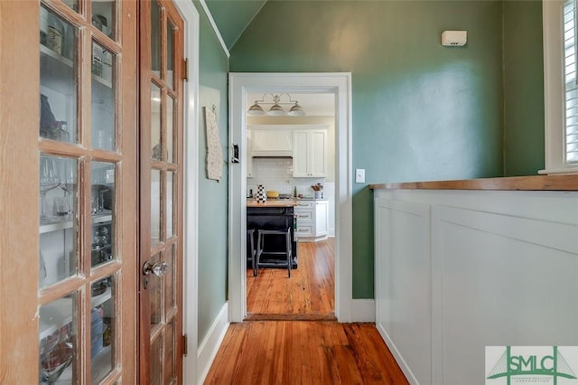 hallway featuring wood finished floors and vaulted ceiling