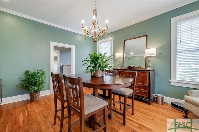 dining space with an inviting chandelier, baseboards, crown molding, and light wood-style floors