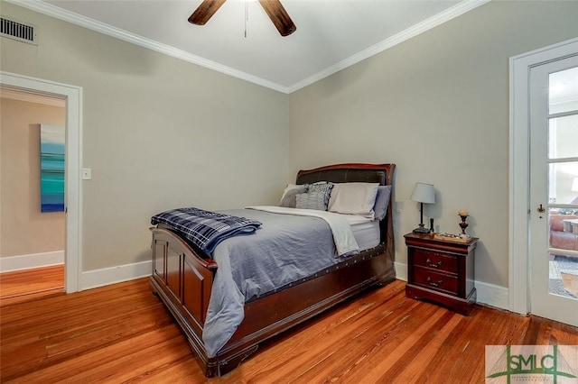 bedroom featuring visible vents, baseboards, wood finished floors, and crown molding