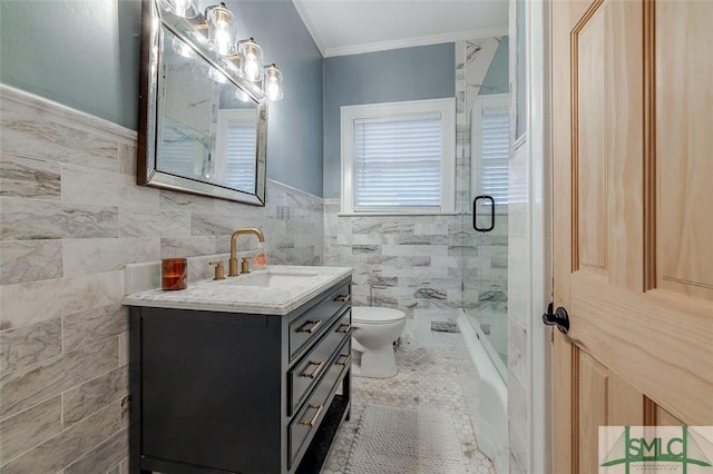 full bath featuring toilet, ornamental molding, tile walls, bath / shower combo with glass door, and vanity