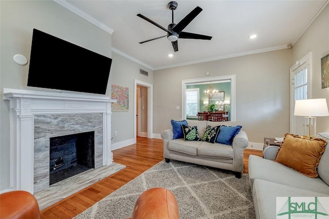 living area featuring a healthy amount of sunlight, wood finished floors, visible vents, and ornamental molding