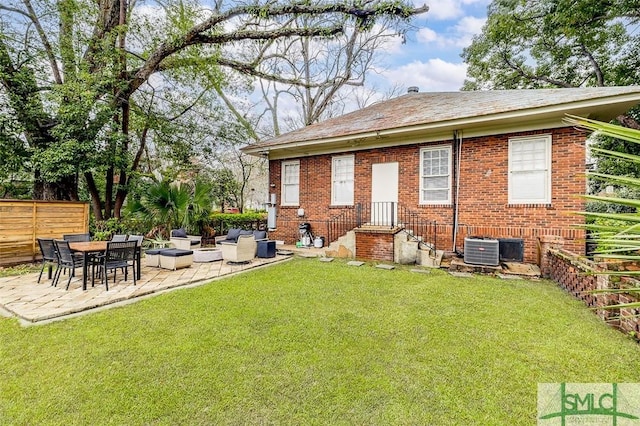 rear view of property with a lawn, a patio, fence, brick siding, and central AC unit