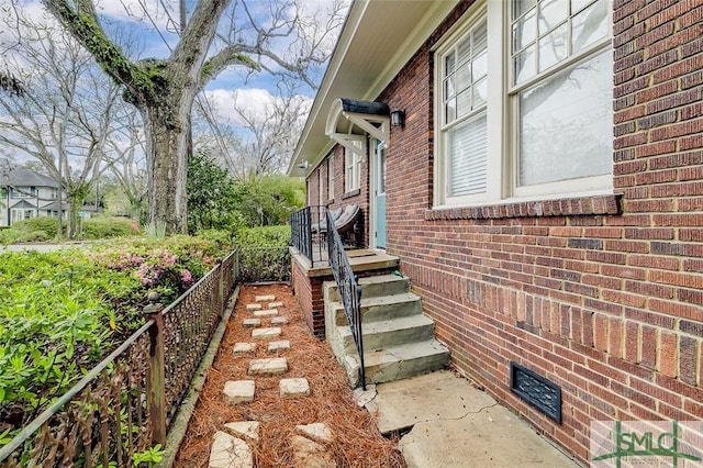 view of property exterior with brick siding and fence