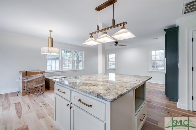 kitchen with visible vents, light wood-style flooring, a ceiling fan, white cabinets, and hanging light fixtures