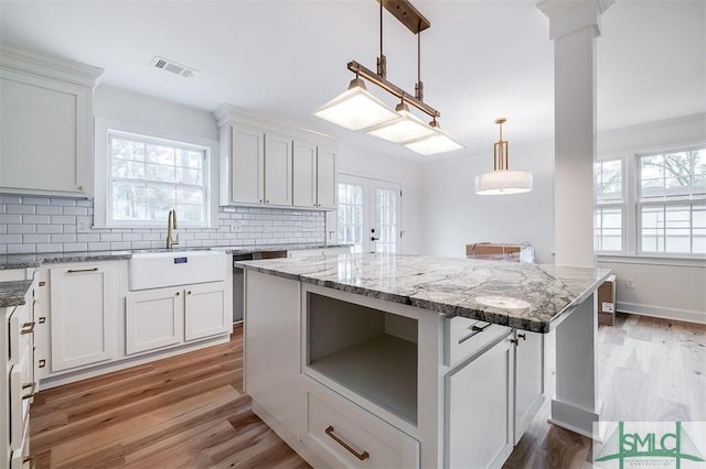 kitchen with tasteful backsplash, visible vents, light wood-style flooring, and a center island