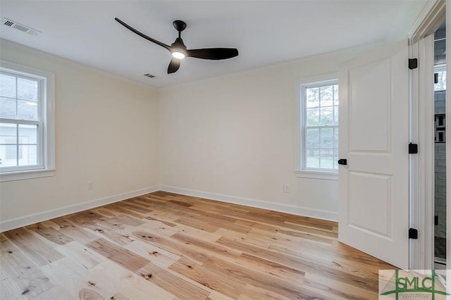 spare room with plenty of natural light, light wood-style flooring, and crown molding