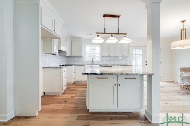 kitchen with decorative backsplash, white cabinets, light wood-type flooring, and a sink