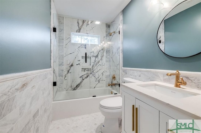 full bath featuring toilet, tile walls, vanity, and shower / bath combination with glass door