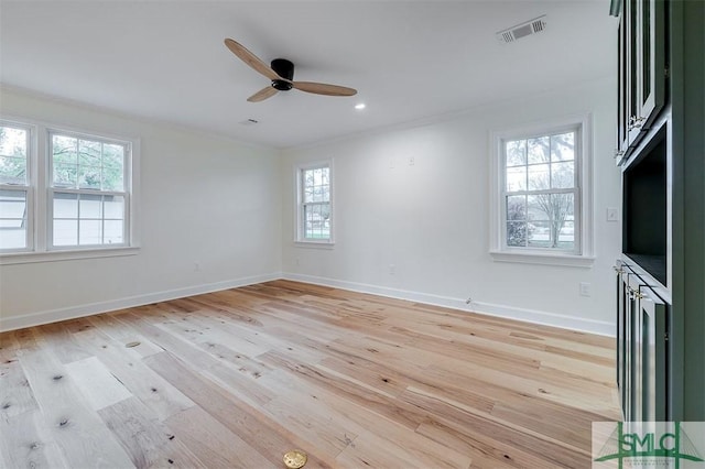 spare room featuring visible vents, baseboards, ornamental molding, and light wood finished floors