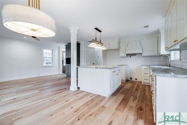 kitchen featuring light stone countertops, light wood-type flooring, backsplash, and a sink