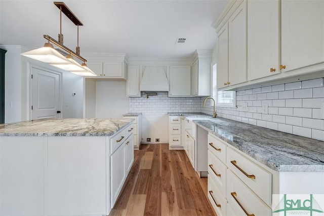 kitchen with visible vents, white cabinetry, wood finished floors, and a sink