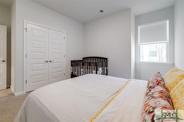 carpeted bedroom with baseboards, visible vents, and a closet