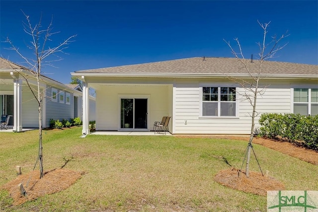 rear view of house featuring a yard, a patio area, and roof with shingles