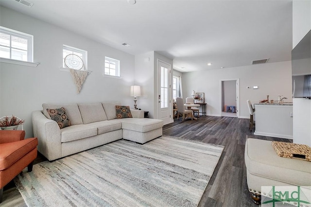 living room with wood finished floors, visible vents, and baseboards