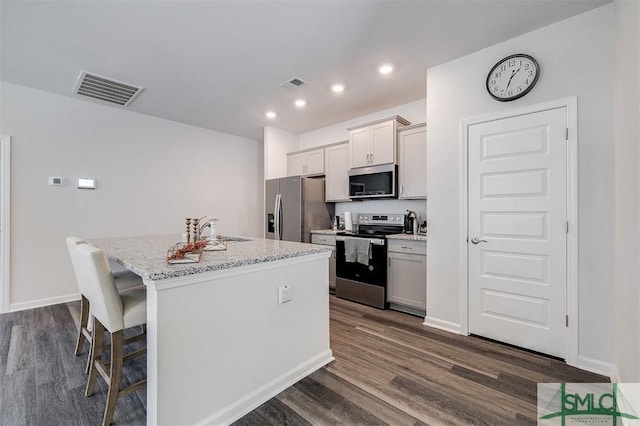 kitchen with visible vents, stainless steel appliances, an island with sink, and dark wood-style flooring