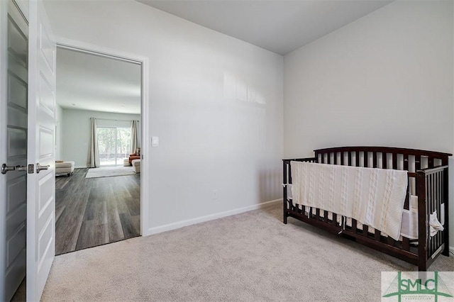 bedroom featuring a crib, baseboards, and carpet