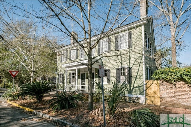 colonial home featuring a porch and a chimney