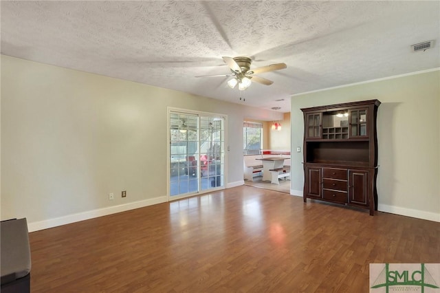 unfurnished living room featuring visible vents, a ceiling fan, a textured ceiling, wood finished floors, and baseboards