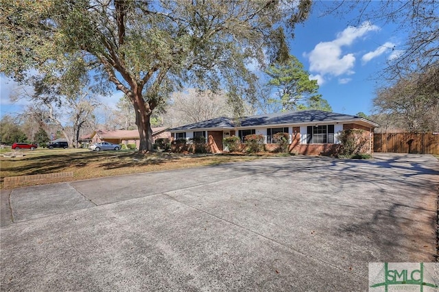 ranch-style home with driveway and fence