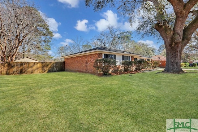 view of home's exterior with a yard, fence, and brick siding