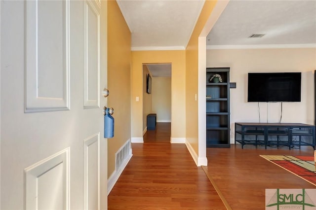 hallway with visible vents, baseboards, wood finished floors, and crown molding