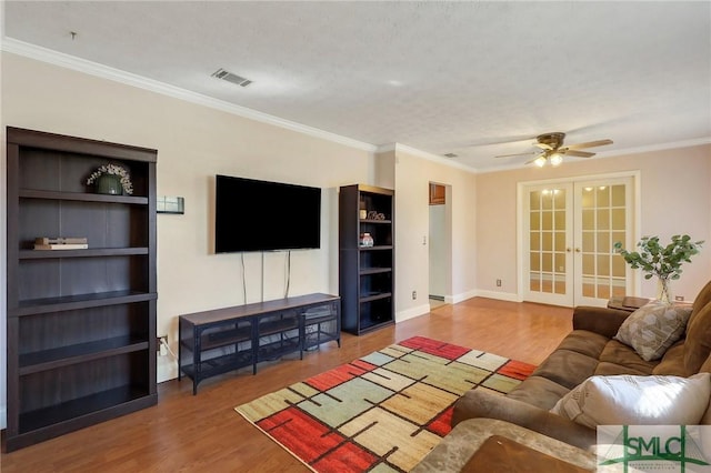 living room with visible vents, a ceiling fan, wood finished floors, french doors, and crown molding