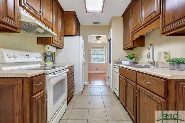 kitchen featuring white appliances, light tile patterned floors, a sink, light countertops, and under cabinet range hood