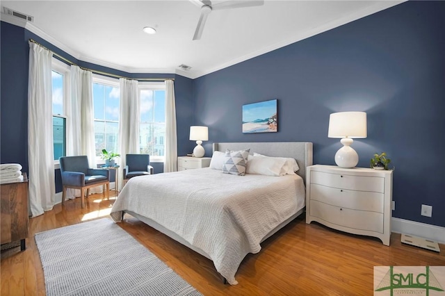 bedroom with crown molding, wood finished floors, visible vents, and baseboards