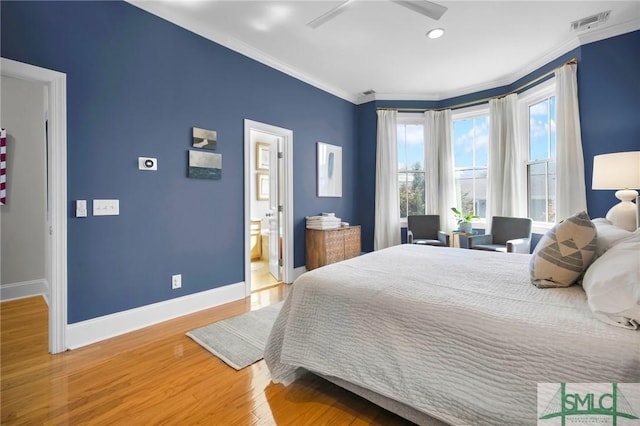 bedroom with visible vents, baseboards, ornamental molding, wood finished floors, and ensuite bath