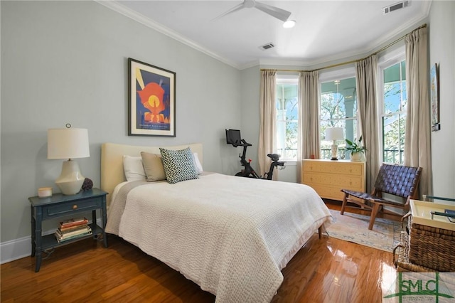 bedroom featuring visible vents, wood finished floors, baseboards, and ornamental molding