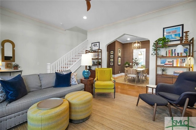 living area with stairway, wood finished floors, recessed lighting, arched walkways, and crown molding