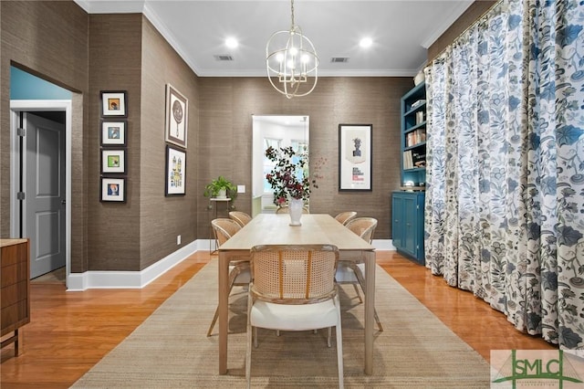 dining area with visible vents, baseboards, light wood finished floors, crown molding, and a chandelier