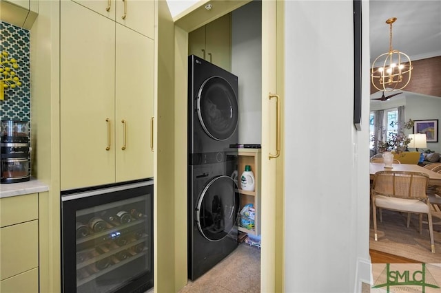 laundry area with laundry area, stacked washer and dryer, beverage cooler, and a chandelier