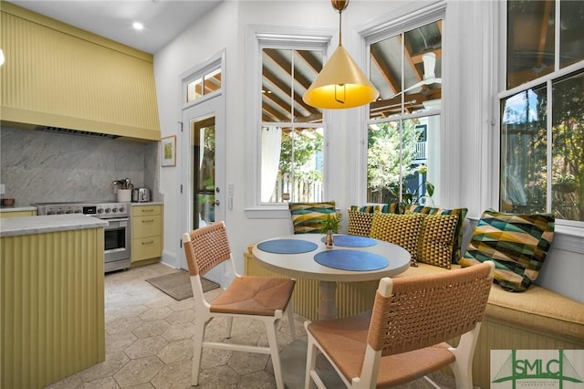 interior space featuring backsplash, light countertops, stainless steel range with electric cooktop, cream cabinets, and custom exhaust hood